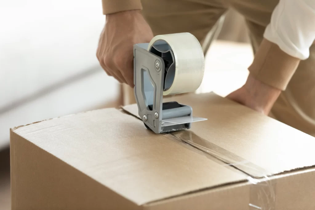 Person using customizes printed acrylic packaging tape on corrugated box for product packaging and shipping