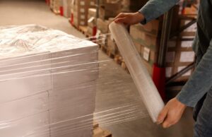 Person using stretch film for packaging industrial products.